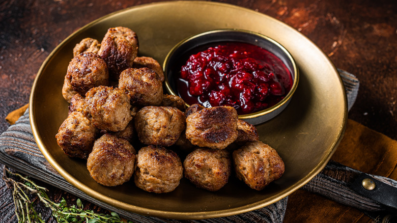 Closeup of meatloaf balls on a plate with cranberry dipping sauce