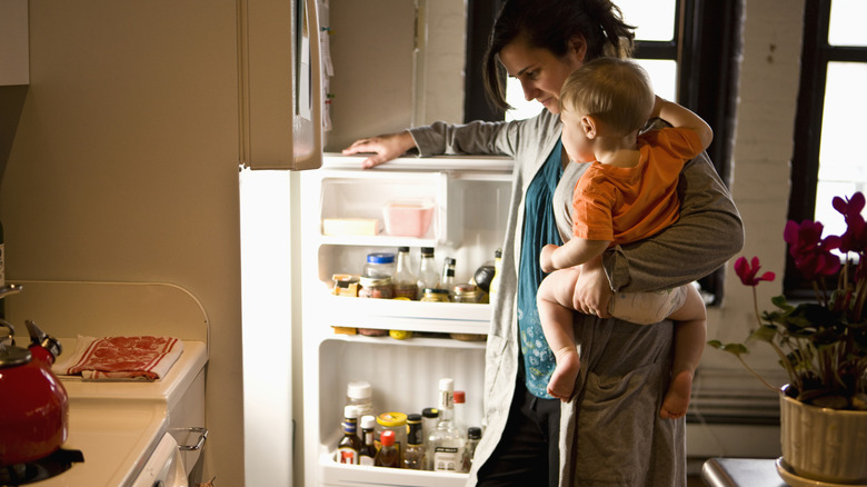 Person opening a fridge door in a kitchen