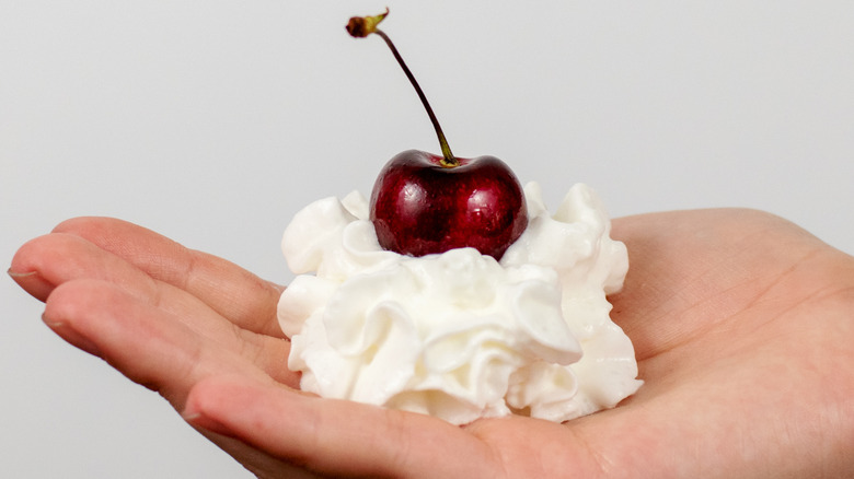 hand holding cherry whipped cream