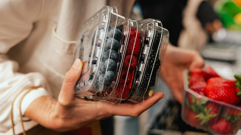 a hand holding multiple fruit containers