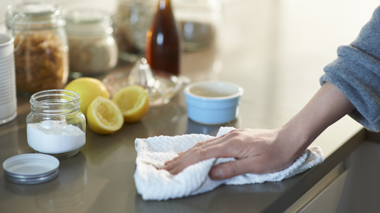 Woman cleaning a kitchen counter with baking soda and lemon