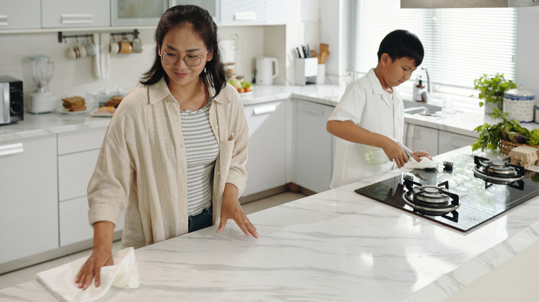 Mother and son cleaning kitchen countertop