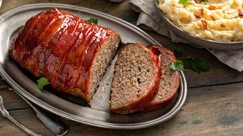 Ketchup-glazed, bacon-wrapped meatloaf sliced on a tray