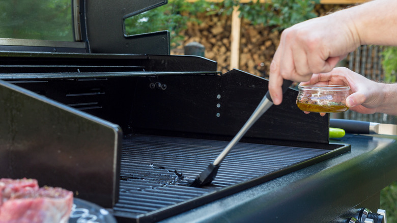 Person oiling barbecue grate with silicon brush
