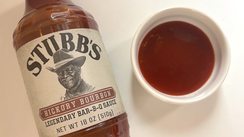 Bottle of Stubb's Hickory Bourbon Bar-B-Q Sauce next to small white dish of sauce on white table