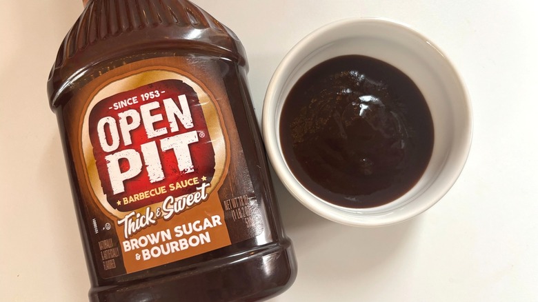 Bottle of Open Pit Brown Sugar Bourbon BBQ Sauce next to small white dish of sauce on white table