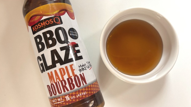 Bottle of Kosmos Q Maple Bourbon BBQ Glaze next to small white dish of glaze on white table