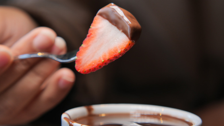 Fork dipping strawberry into chocolate fruit dip