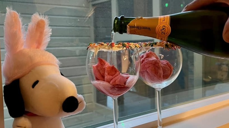 Champagne being poured into wine glasses with frosting and sprinkle rims