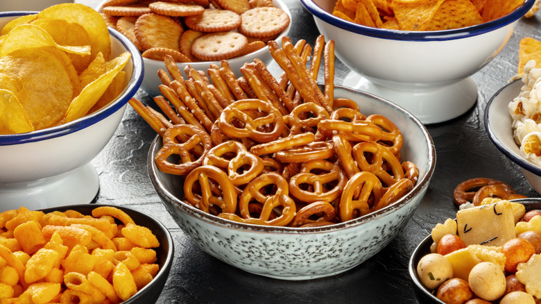 Variety of salty snacks in bowls on table