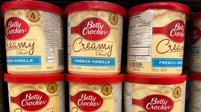 Several stacked tubs of Betty Crocker Creamy Deluxe French Vanilla frosting