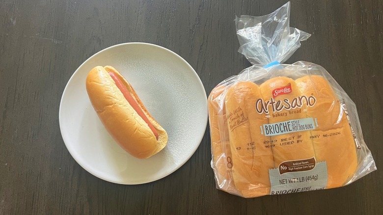 Sara Lee Artesano Brioche Style Hot Dog Buns pack with one assembled hot dog on a white plate
