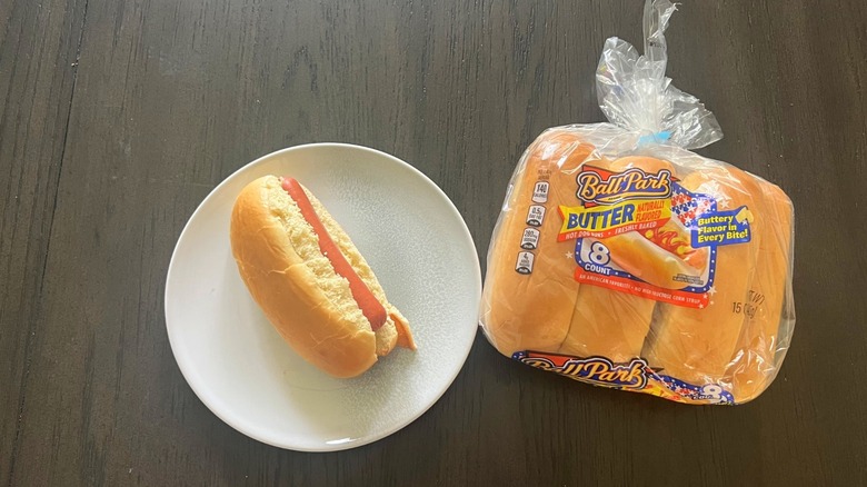 A bag of Ball Park Butter Hot Dog Buns with assembled hot dog on plate