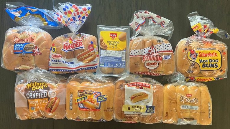 Top view of nine different brands of hot dog buns bagged and laid on a dark table