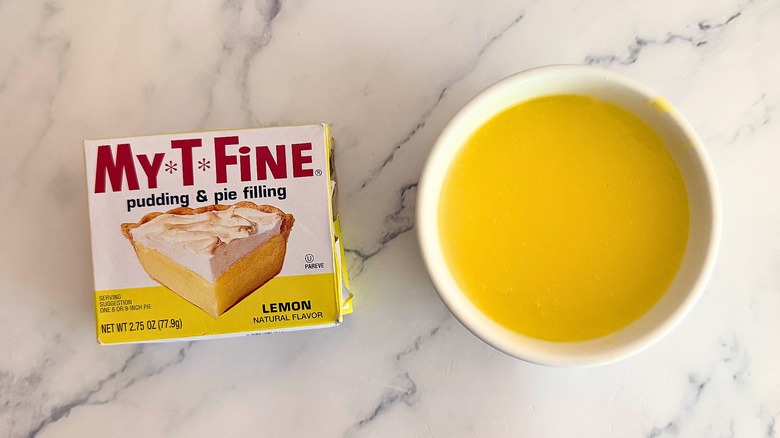 My-T-Fine lemon pie filling in white cup next to packaging on marble surface