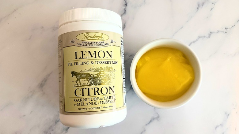 Rawleigh lemon pie filling in white cup next to packaging on marble surface