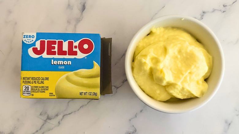 Jell-O Sugar Free lemon pie filling in white cup next to packaging on marble surface