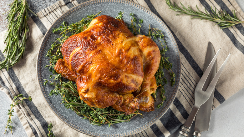 rotisserie chickens on plate with knife and rosemary