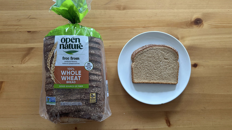 Open Nature 100% Whole Wheat Bread package and slice on a white plate on a table