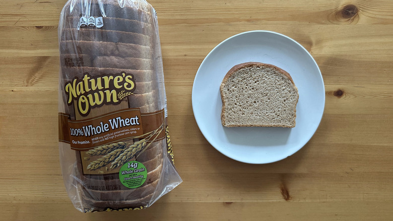 Nature's Own 100% Whole Wheat Bread package and slice on a white plate on a table