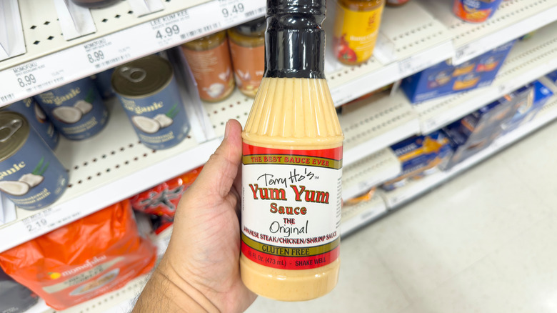 Foodie holding a bottle of Terry Ho's yum yum sauce in a grocery store