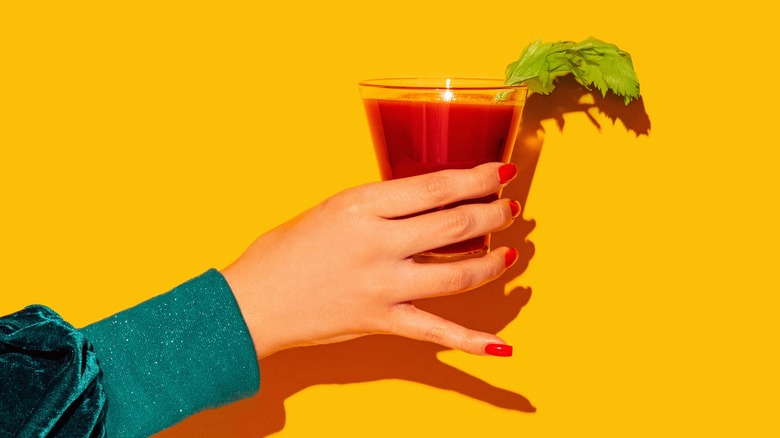 Person holding bloody mary on yellow background