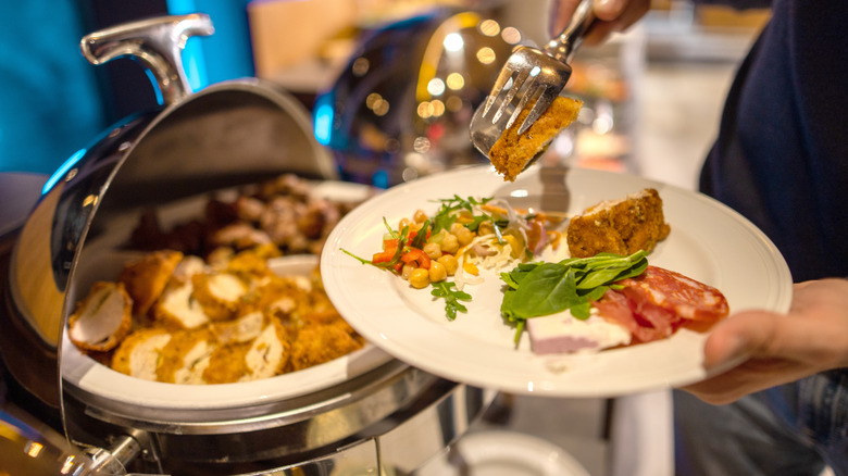A buffet with person piling food onto their plate