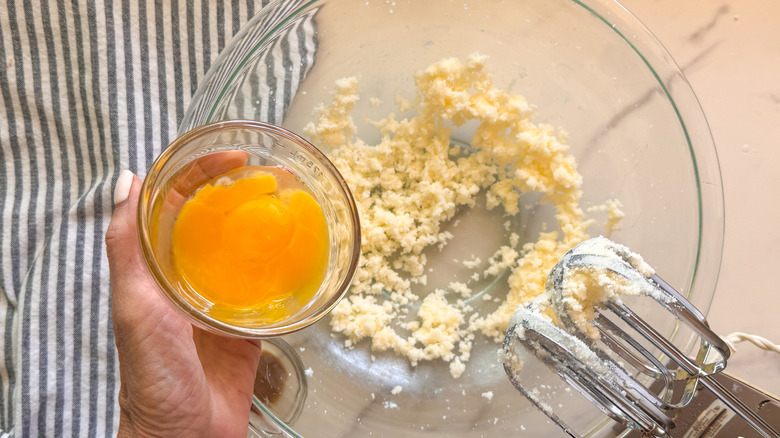 hand adding yolks to bowl