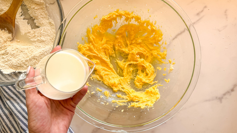 hand adding milk to bowl