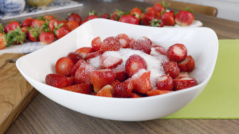 A bowl of strawberries covered in granulated sugar