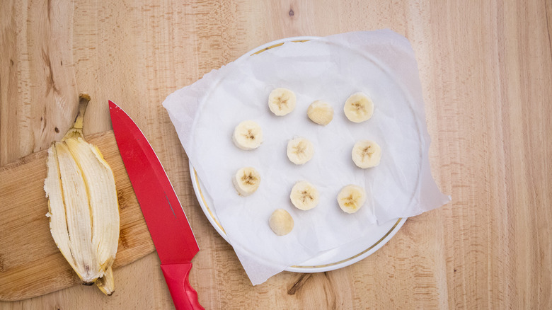 banana slices on lined plate with banana peel and knife nearby