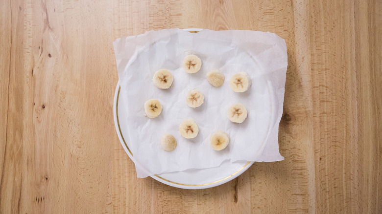 frozen bananas on white plate lined with parchment paper