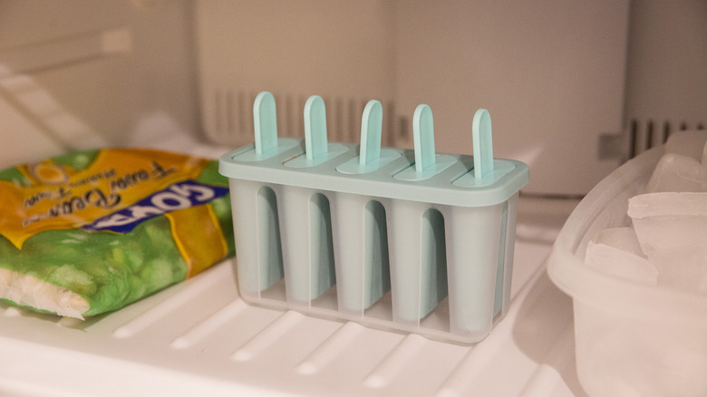blue popsicle mold in freezer next to box of ice