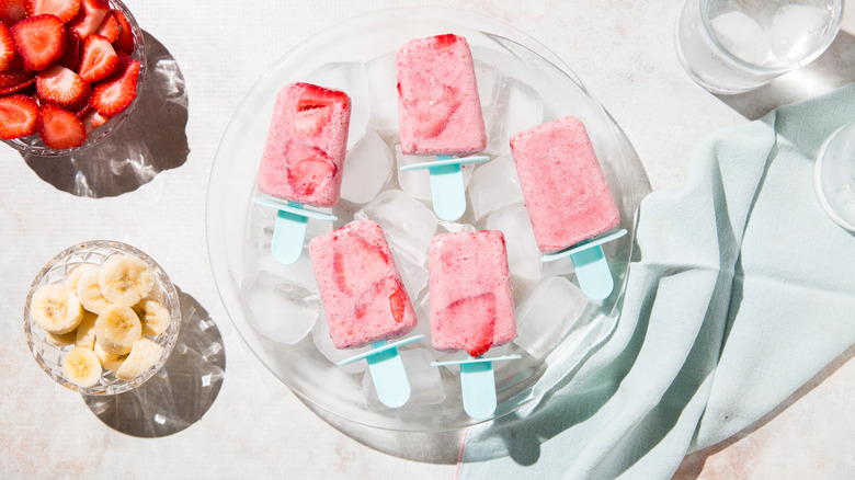 fruit popsicles served over ice on table next to bowls of fruits