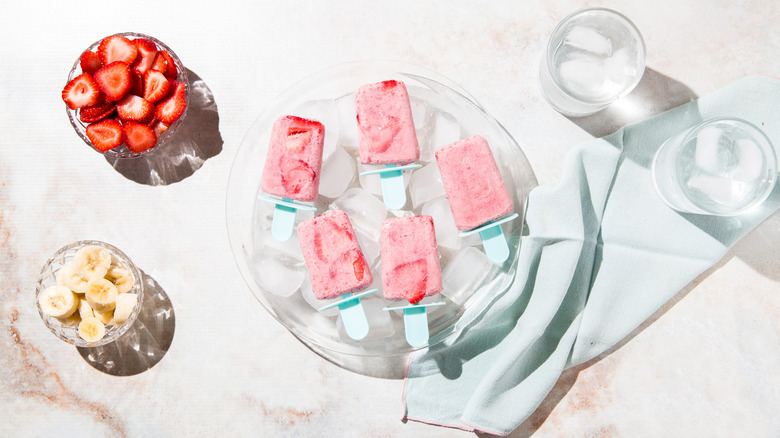 fruit popsicles served over ice on table next to cups of ice water and fruit bowls