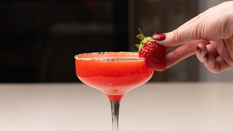 garnishing cocktail with a strawberry