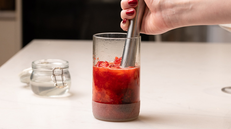 muddling strawberries in tall glass