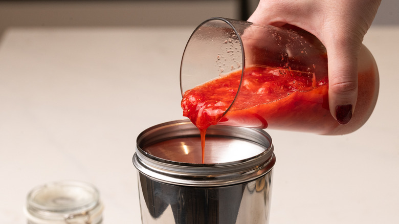 straining muddled strawberry mixture