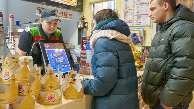 Burger King employee serving customers at the cashier