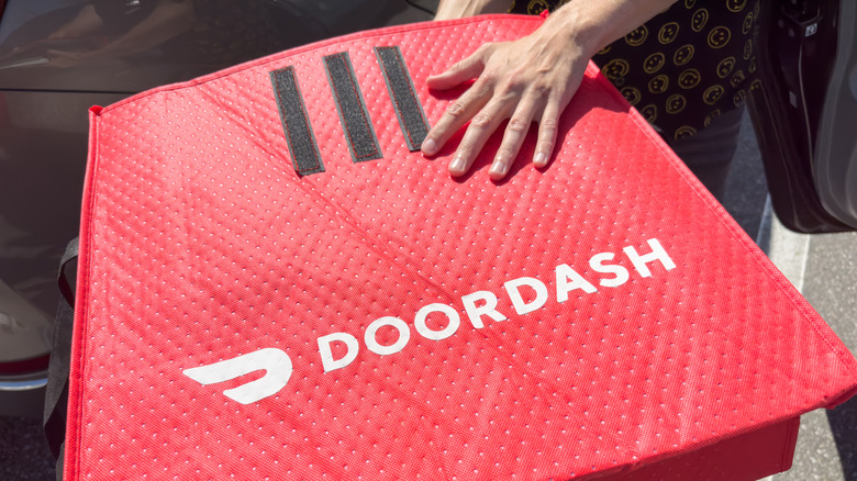 A hand on top of a DoorDash food delivery hot bag