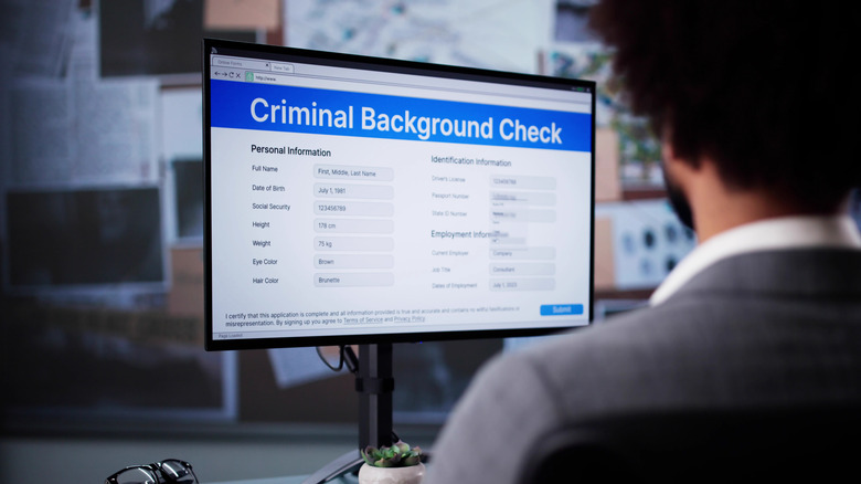 A man sitting in front of a computer conducting a criminal background check