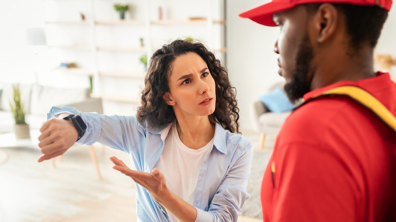An angry woman showing her watch to a delivery driver
