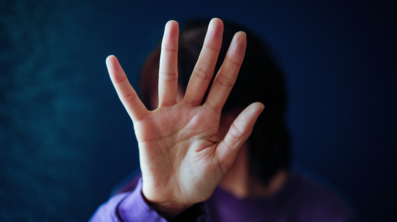 A woman holding her hand in front of her face