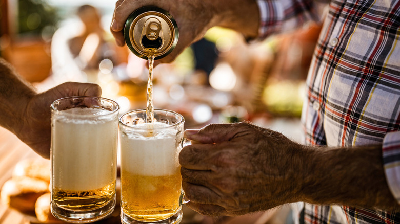 person pouring beer from can into glass