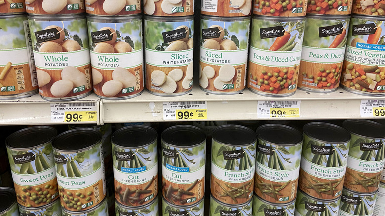 The grocery store shell stacked with cans of whole potatoes, peas and carrots, mixed vegetables, green beans, and peas