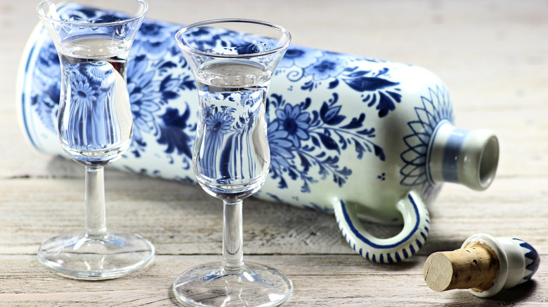 Genever served in tulip glasses next to ceramic bottle.