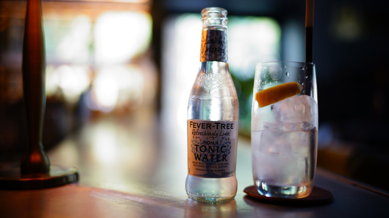 Bottle of Fever Tree tonic water next to gin and tonic.