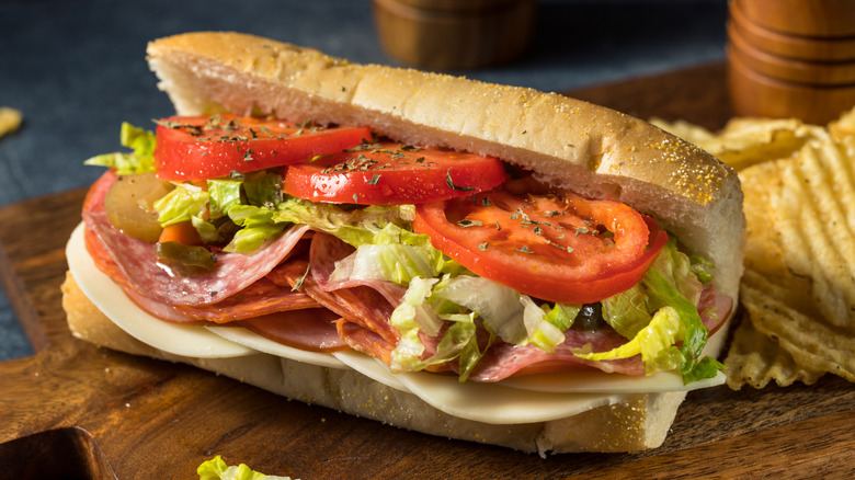 Italian hoagie with lettuce, tomatoes, and deli meats with potato chips