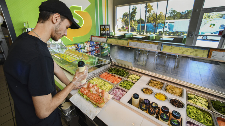 Subway worker making sandwich behind counter