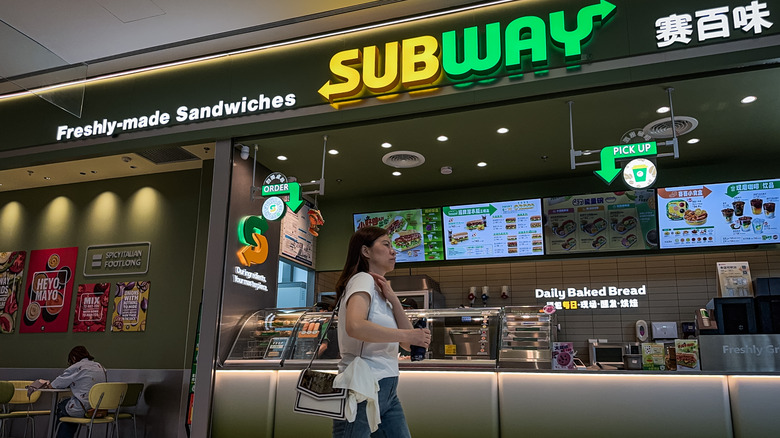 A woman walking past a Subway counter